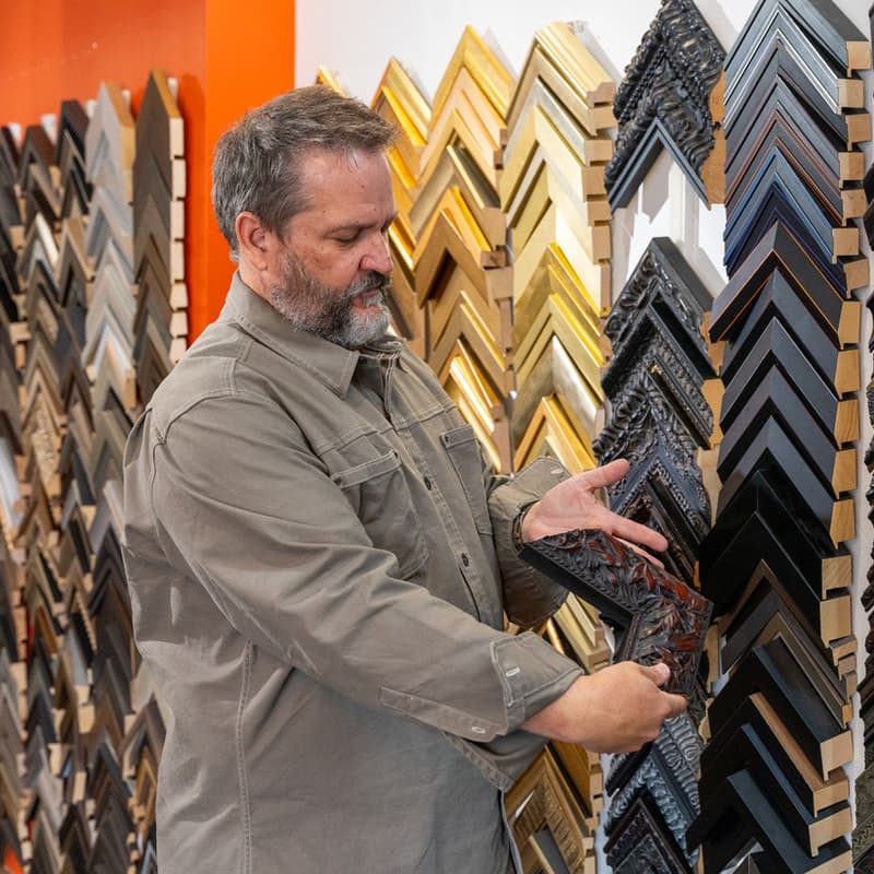 Custom framing expert selecting frames at Pixels Foto & Frame